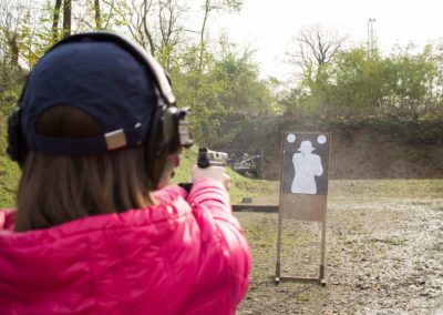 kobieta w czapce i różowej kurtce strzela z pistoletu 9x19mm w fabryce strzelania